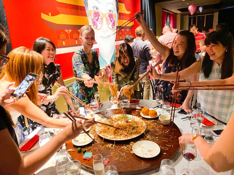 Adobe Singapore employees tossing together a large plate of Yu Sheng at a restaurant to ensure a lucky, prosperous and healthy year for all.