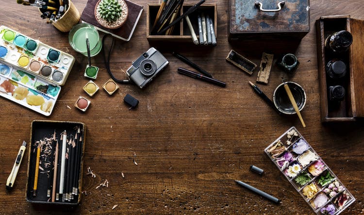 Aerial view of artistic equipment and painting tools on wooden table.
