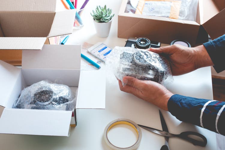 Online shopping concepts with young person wrapping product to the box.