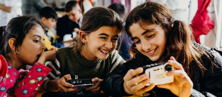 Three young girls looking at the screen on a camera.