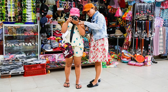 Two women taking a picture on a camera. 
