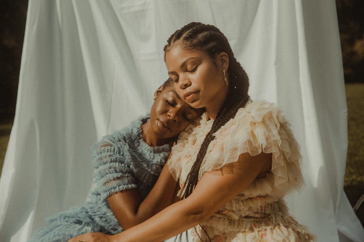 Two women leaning on one another. 