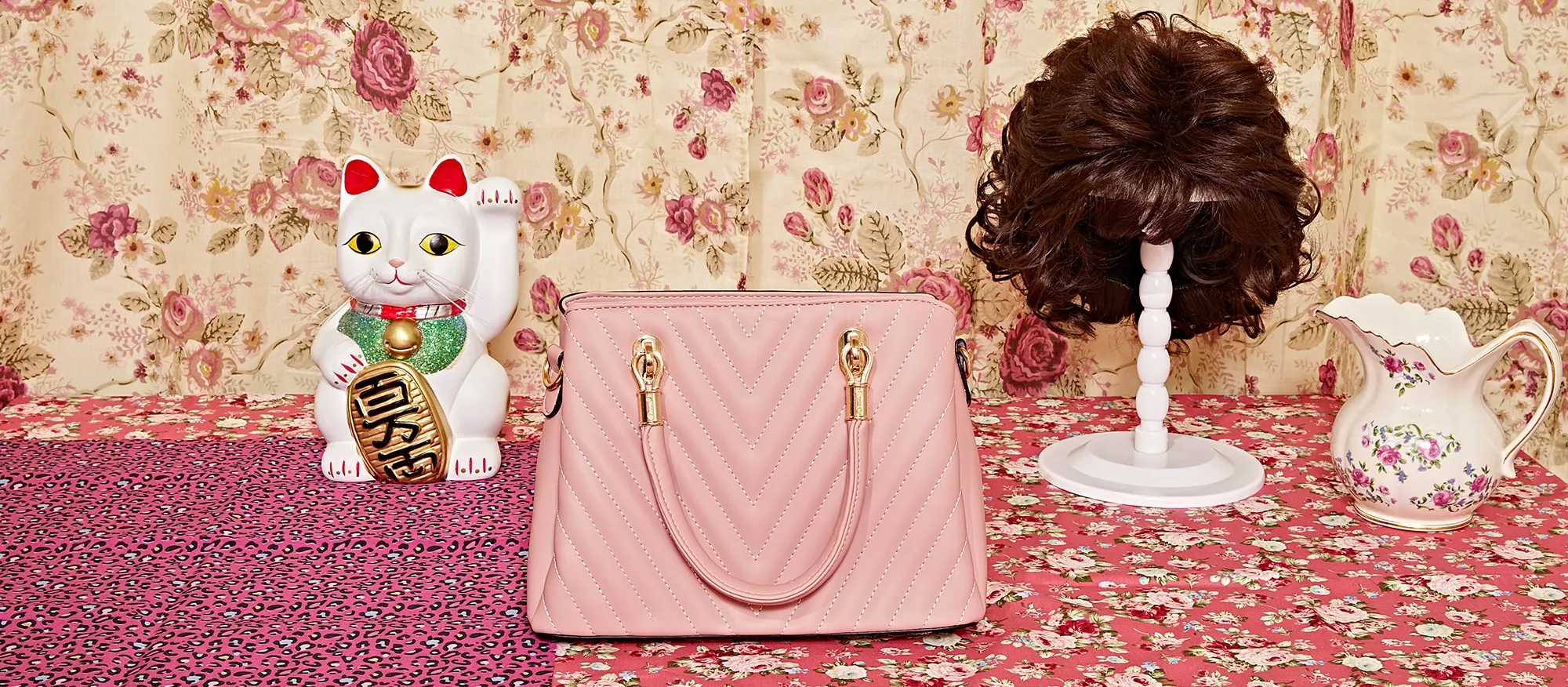Photo of a pink purse and wig on a tablecloth. 