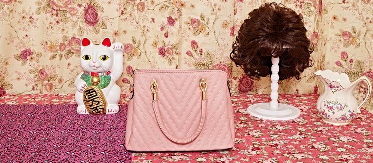 Photo of a pink purse and wig on a tablecloth.