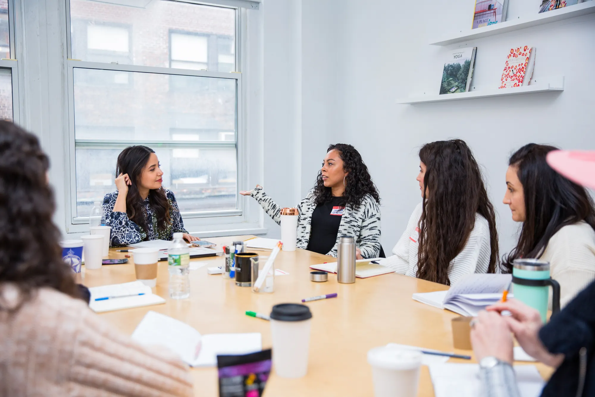 Image of Lisa Nicole Rosado and other women entrepreneurs around a conference room table having a conversation.