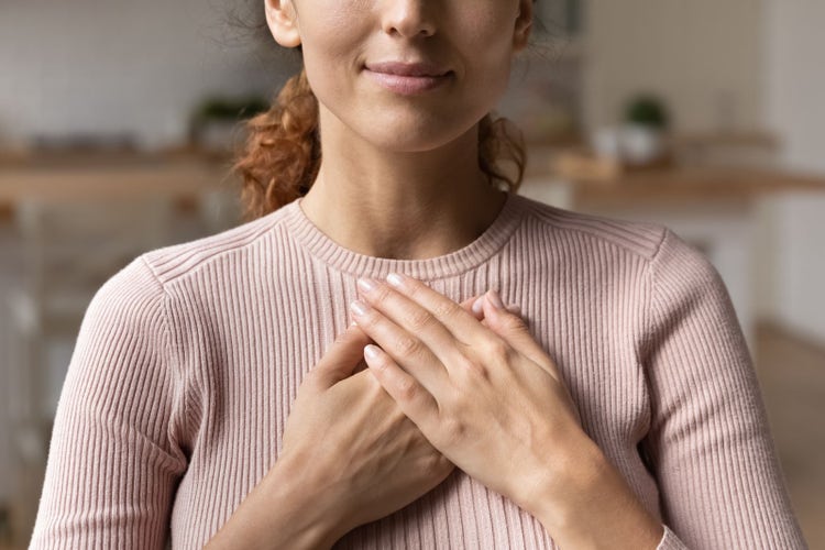 Image of woman with her hands to her chest. 