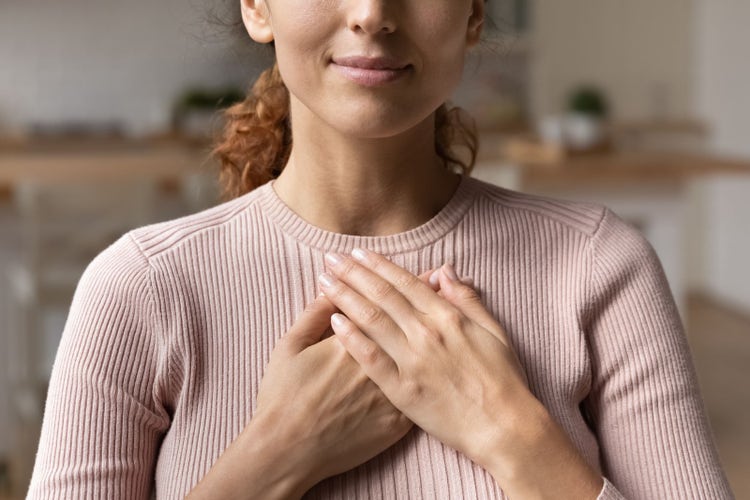 Image of woman with her hands to her chest.