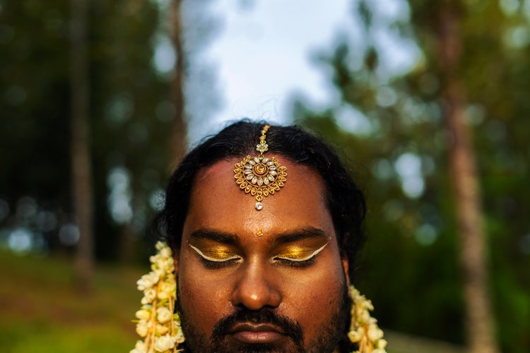 Portrait of dark skinned Indian non-binary individual with traditional female attire in park.