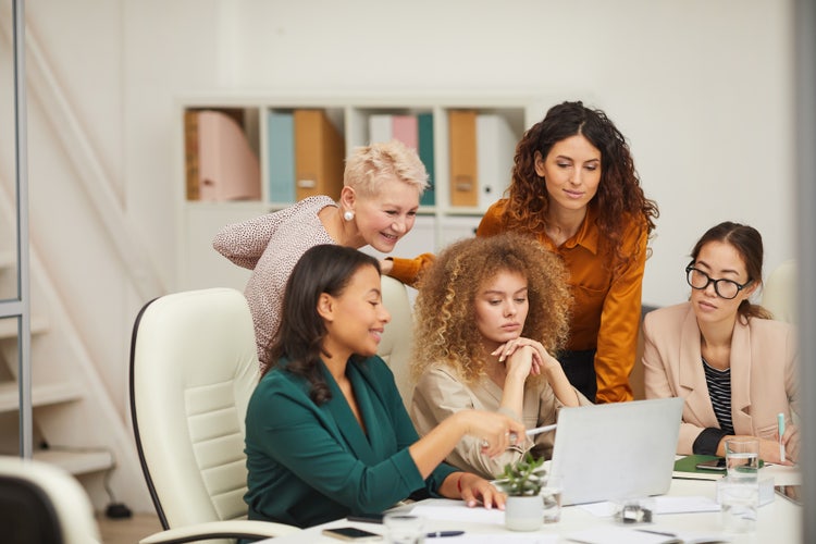 five women looking at a laptop screen
