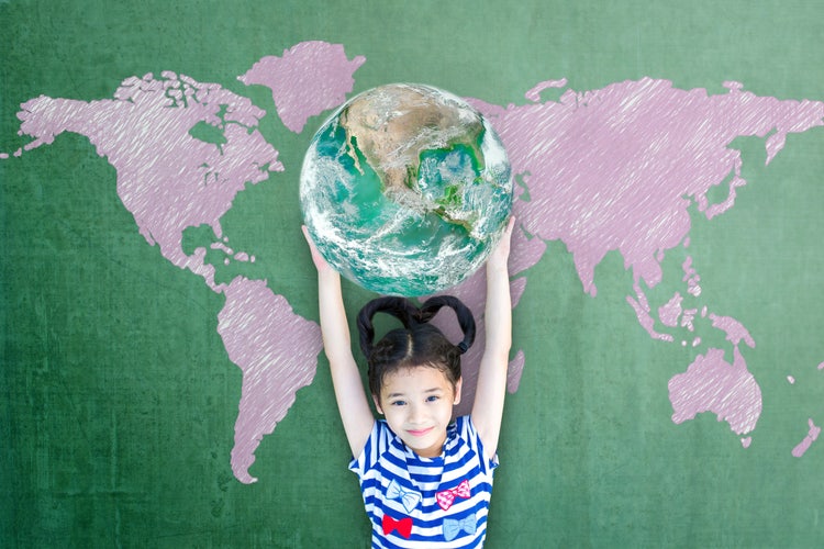 Happy child raising globe on school chalkboard for world literacy and gender equality concept.