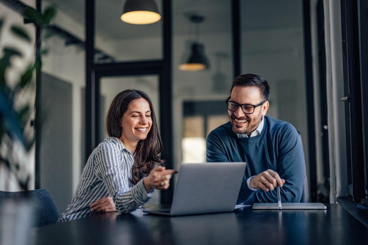 A man and woman working together in the office. 