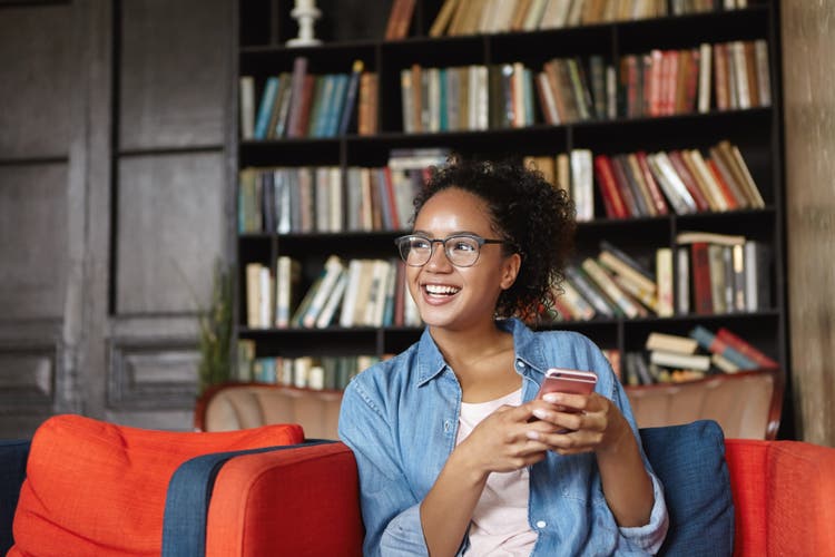 Image of woman holding a cell phone and smiling.