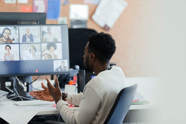 Businessman video conferencing with coworkers on computer screen.