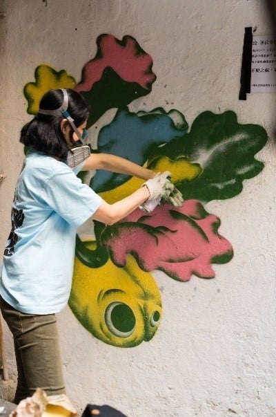 Angela Ho spray painting her art onto a wall