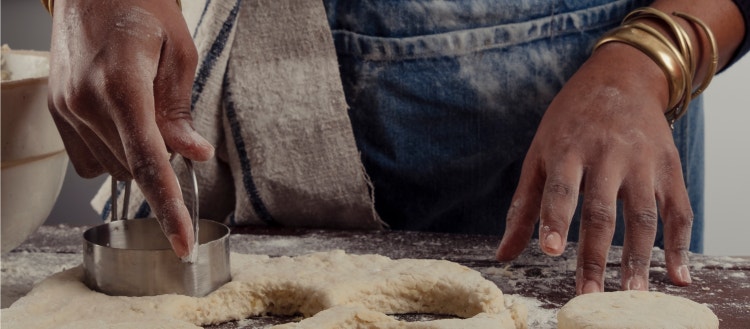 Woman chef cutting biscuits out of dough.