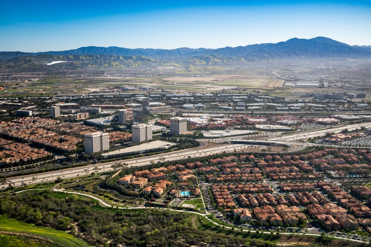 Aerial photography of a region in Southern California with a view of residential, and commercial areas. Rolling hills can be seen in the background.