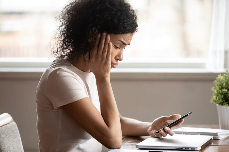 Woman looking at mobile phone screen feels upset.