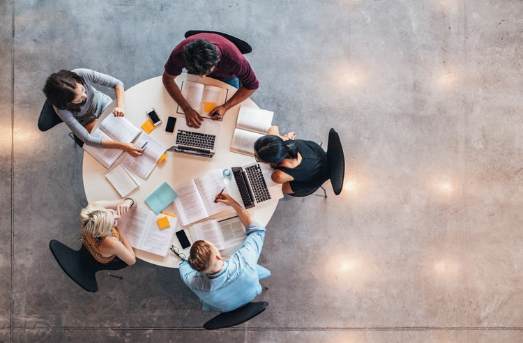 birds eye view of five students studying around a round table. 