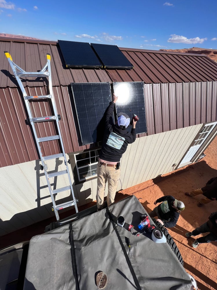 Photograph by Mylo Fowler of a group of people installing solar panels and electricity on the Navajo Reservation