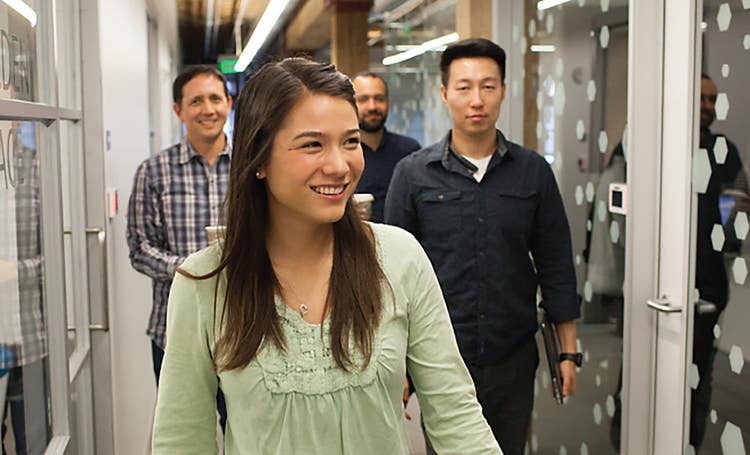 Woman walking down hallway at the front of a group.