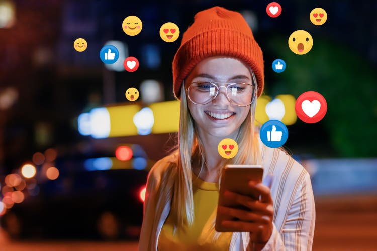 Girl looking at phone with emojis flying around her