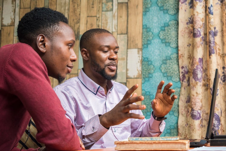 Man explaining something to a colleague in the office with a laptop.