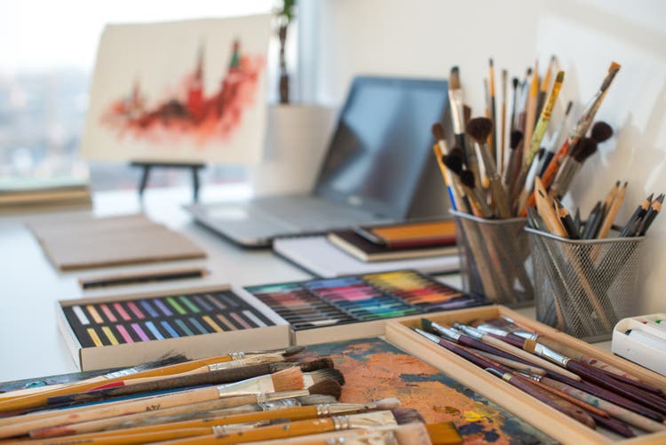 Art supplies next to a laptop