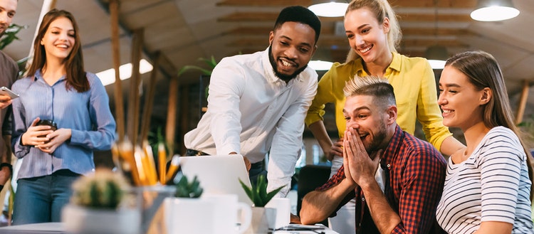 Group of people smiling and looking at a computer screen. 