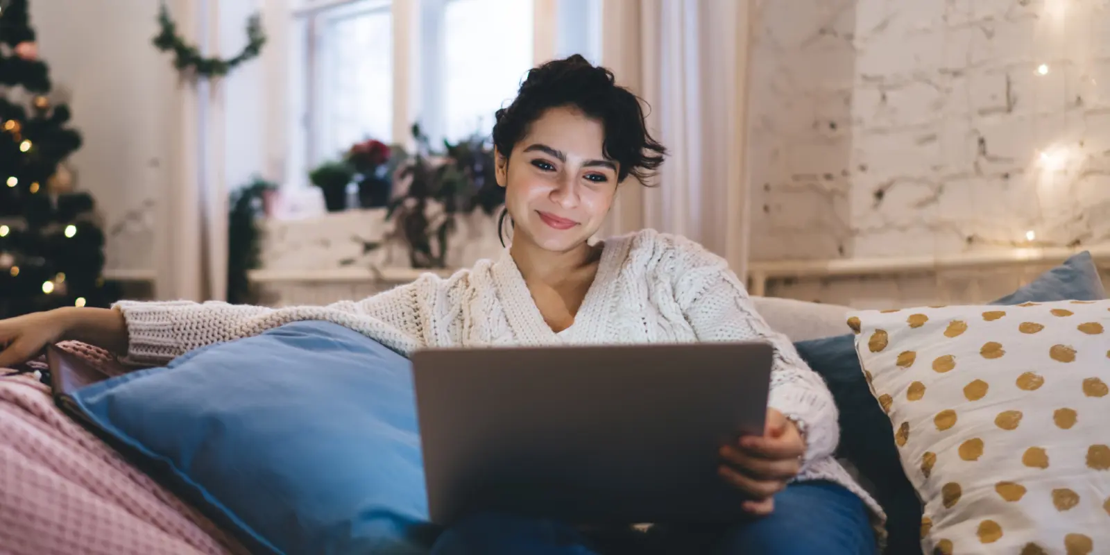 Woman looking at a laptop while sitting on the couch.