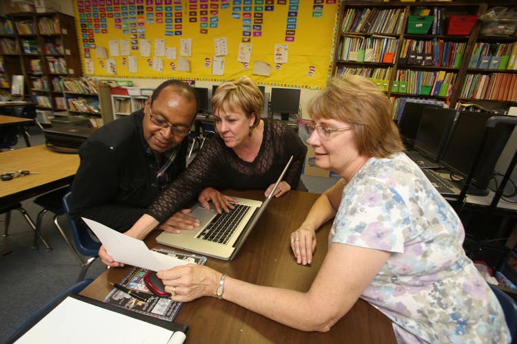 Image of three people working on a project on a laptop.