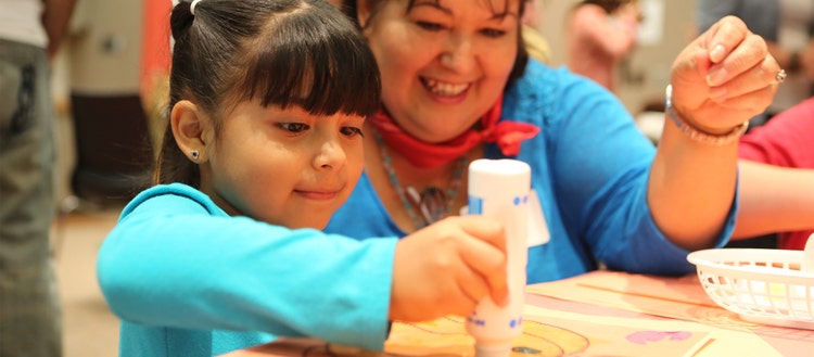 Woman helping a child with an art project.