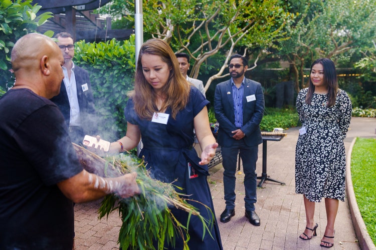 Woman smelling smoke in traditional smoking ceremony.