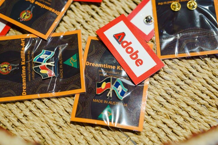 Pin on badges of the Adobe 'A' and of the Aboriginal flag.