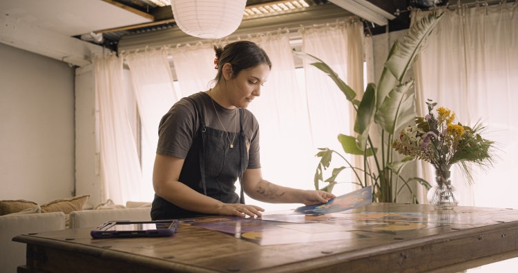 Indigenous artist Desirai Saunders sorting through her printed illustrations