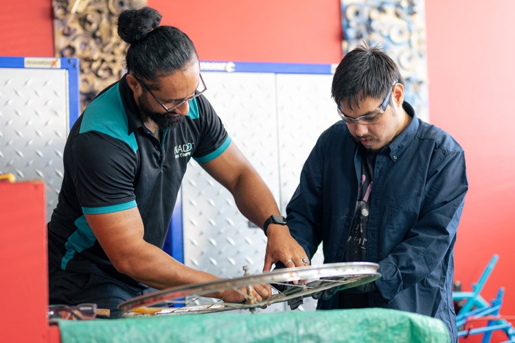 NADO Disability Services worker and participant working on a bike wheel