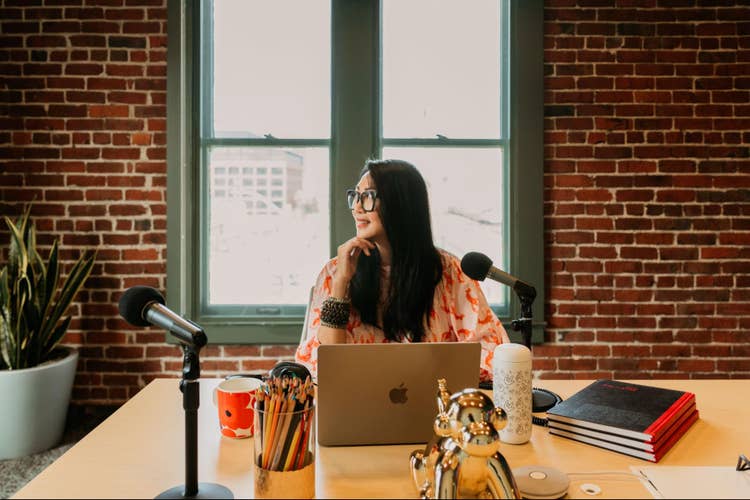 Woman sitting at a computer creating a podcast.