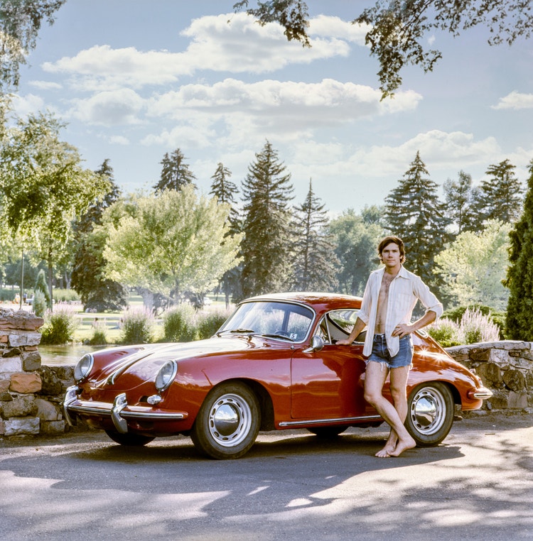 Image of a man standing beside a red sports car.