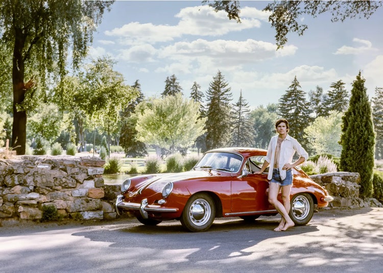 Image of a man standing beside a red sports car.