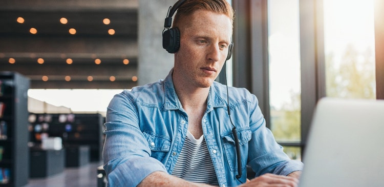 Image of man with headphones on a laptop.