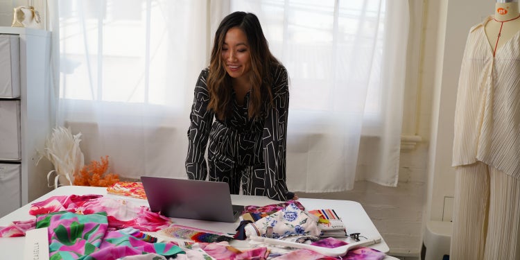 Showpo CEO Jane Lu on laptop surrounded by fabric samples