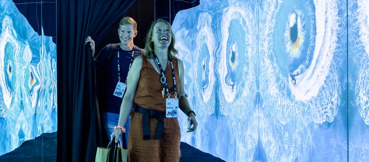 Two smiling people walking through a blue hallway.