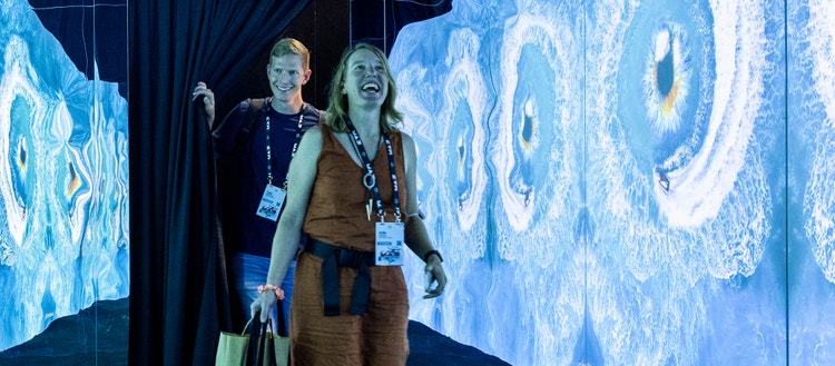 Two smiling people walking through a blue hallway.