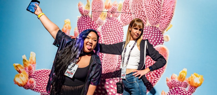 Two women standing in front of a wall decorated with a pink cactus