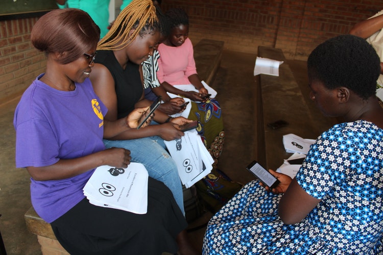 Group of women together looking at thier phones.