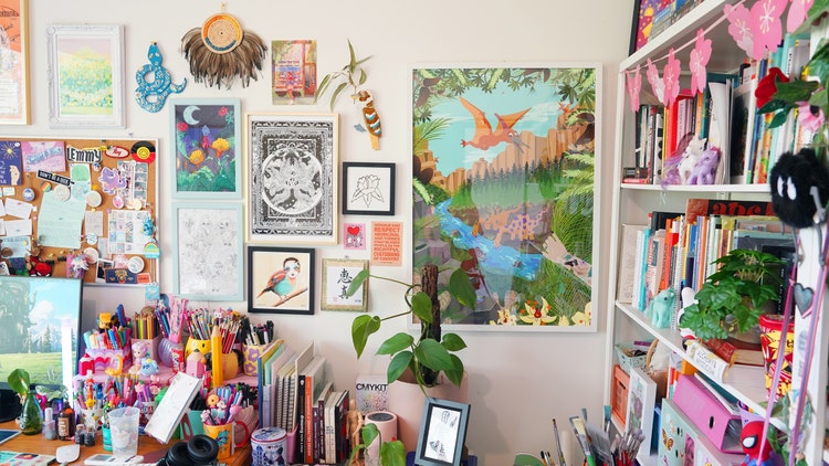Studio space with various artworks on walls, bookshelves and plants