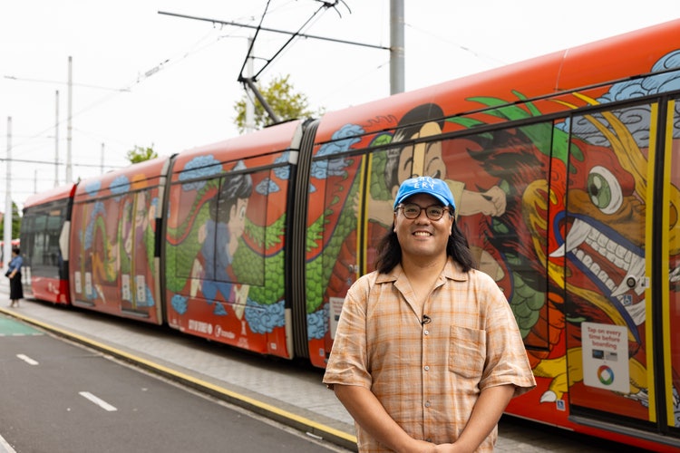 Andrew Yee in front of a tram covered in artwork