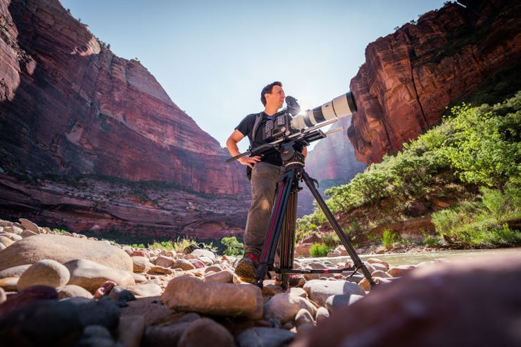 Image of a man with a camera on a tripod.