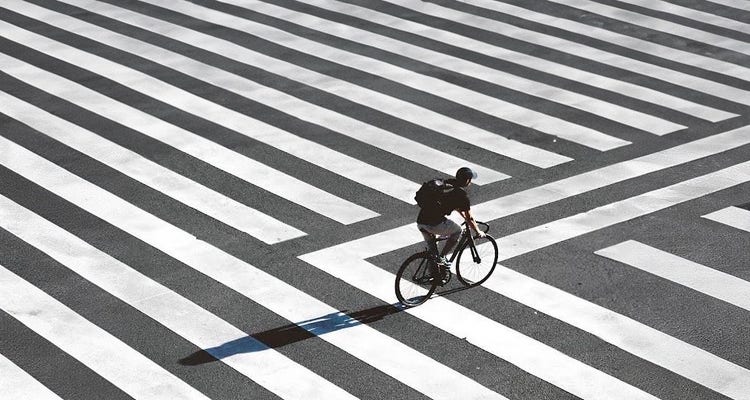 Image of a man on a bicycle riding on the street. Source Toni Shinobi.
