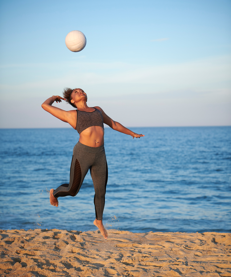 Women playing volleyball on the beach.