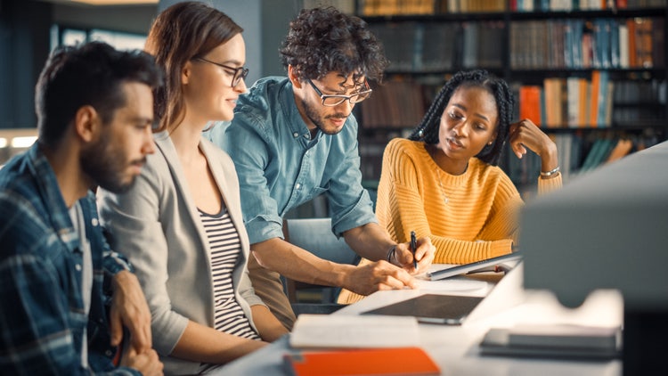 Image of colleagues collaborating at a table in a library.